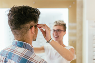 Sticker - Attractive young couple in optical store buying glasses and smiling