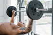 athletic bare-chested tattooed sportsman lying on bench and lifting barbell in gym