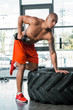© LIGHTFIELD STUDIOS - handsome tattooed african american sportsman exercising with dumbbell at gym