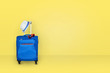 Leinwandbild Motiv Blue suitcase with a summer hat and fashionable  sunglasses on light yellow background, a summer vacation travel concept, free space with a place for copying.