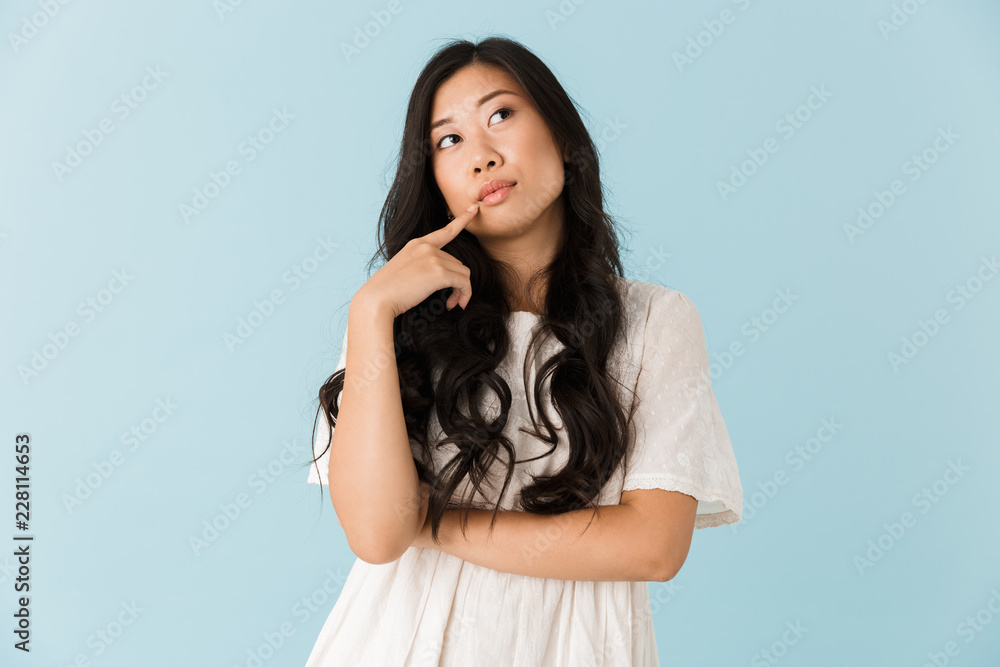 Thinking young asian beautiful woman posing isolated over blue ...