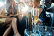 © Kzenon - Women and men celebrating with drinks in a limousine car, focus on the alcohol bottle