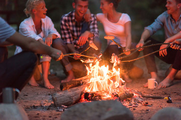 young friends relaxing around campfire