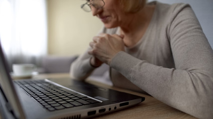 Retired female watching video on computer, delighted to see her grandchildren