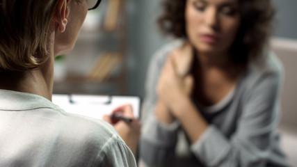 Female psychologist listening to young lady during personal session, depression