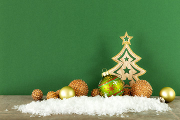 christmas decoration green background with wooden tree glass balls and snow