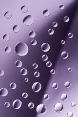 close-up view of transparent calm droplets on purple background