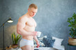 © satyrenko - Sexy handsome young man standing shirtless in his bedroom, holding a coffee cup