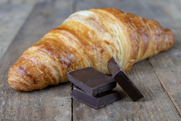 Wall Mural - Tasty well-baked croissant on a wooden kitchen table. Light bread prepared for breakfast.