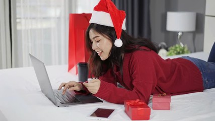 Sticker - happy woman shopping online for Christmas gift with computer laptop and credit card on a bed