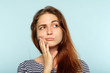facial expression. quizzical grumpy thoughtful woman. young beautiful brown haired girl portrait on blue background.