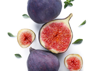 Whole and cut ripe figs on white background