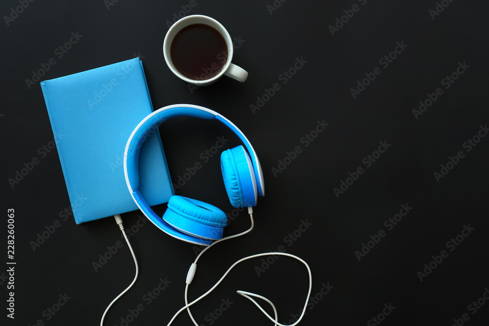 Modern headphones and book on table. Concept of audiobook