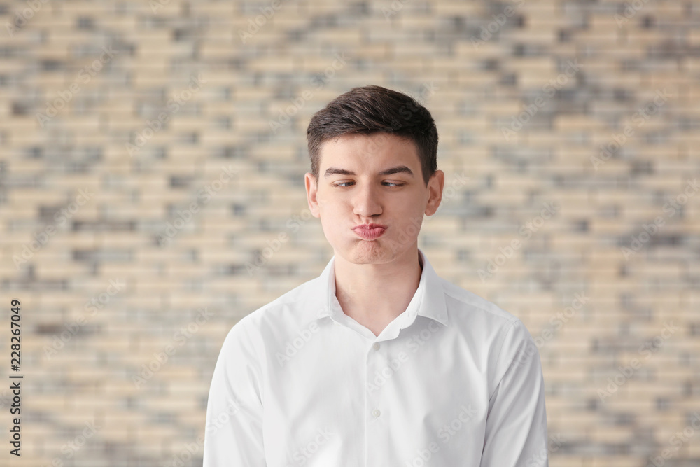 Funny portrait of young man against brick wall