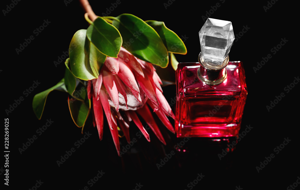 Bottle of perfume with tropical flower on dark background