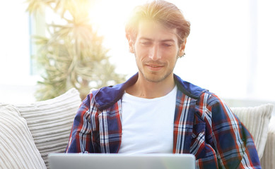 Wall Mural - happy successful young man looking at laptop at home.