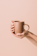 cropped shot of woman holding cup of warming drink isolated on beige