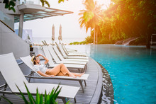 Asian Woman Relaxing By The Pool In A Luxurious Beachfront Hotel Resort At Sunset Enjoying Perfect Beach Holiday Vacation