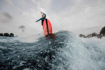 Wall Mural - Active child boy dressed in swimsuit wakesurfing jumping on orange board