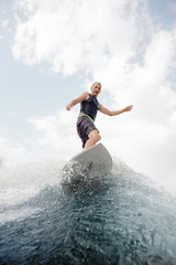 Wall Mural - Young wakesurfer standing on the high blue wave