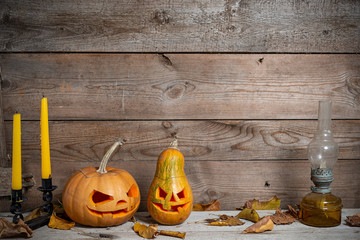 Two decorated pumpkins for a Halloween on a mystical autumn background with candles and gas lamp