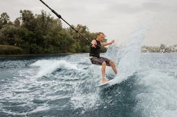 Wall Mural - Active man riding on the wakeboard holding a rope