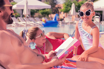 Stylish accessorize. Happy cute girl wearing cats sunglasses while sitting together with her parents