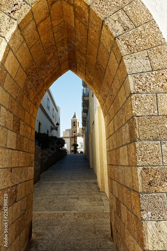 Fotografie, Obraz Blick durch einen Torbogen in Rota in Andalusien zum Castillo de Luna