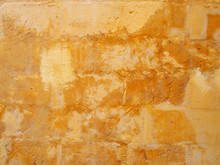 An Old Distressed Patched Yellow Stone Wall Painted In Different Shades Of Faded Stained Bright Yellow Paint