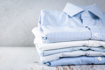 Stack of male folded shirts on rustic background, copy space