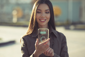 Transparent phones and gadget of the future concept, a beautiful young Asia woman is using an application with her innovative technology transparent mobile smart phone, while out in the city