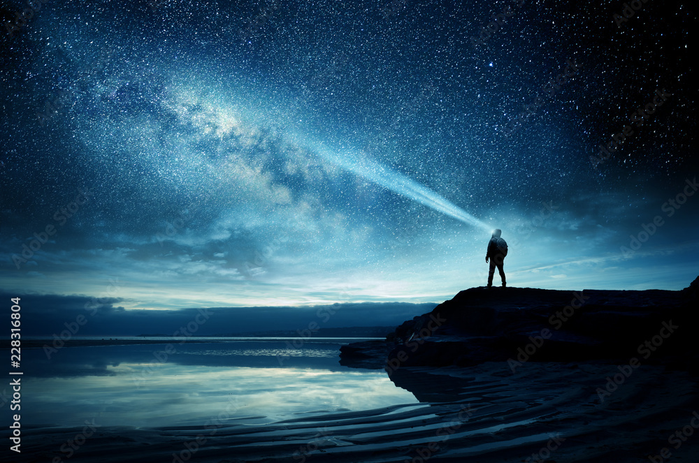 A person standing and watching the Milky Way galaxy rise into the night sky. Photo Composite - obrazy, fototapety, plakaty 