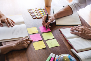 Wall Mural - high school or college student group sitting at desk in library studying and reading, doing homework