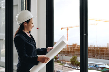 Engineering Consulting People on construction site holding blueprint in his hand. Building inspector. Construction site check drawing and business workflow of new building