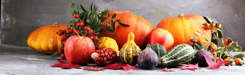 Koncepcja natura jesień. Spadają owoce i warzywa na drewno. Obiad dziękczynny. Śliwki i dynia z słonecznikami i jabłkami.