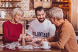 Interesting game. Alert bearded man smiling and playing and putting puzzles together with pensioners