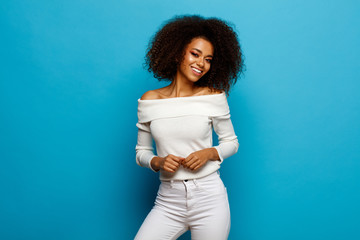 Wall Mural - Beautiful black woman with white teeth and afro is smiling isolated on blue background