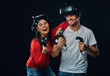 Happy couple of gamers with controllers and VR headsets.