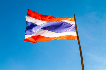 Thai flag waving on the blue sky on the wooden mast and a sunny day in Chiang Mai, Thailand