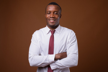 Studio shot of young African businessman against brown backgroun