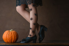 Happy Halloween! Female Feet In Stockings With An Orange Pumpkin.