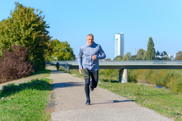 Gray man running along river