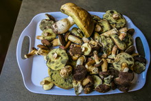 Pile Of Freshly Picked Up European Brown And Yellow Forest Mushrooms, King Bolete And Bay Bolete, Placed On White Plate On A Kitchen Table, Top View