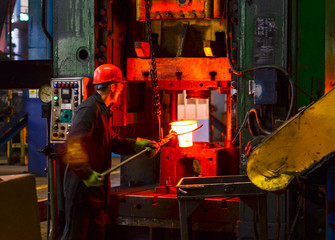 Hot iron in smeltery held by a worker. High precision hot forging product, automotive part production by hot forging process, automatice line hot forging. iron melting recycling work.