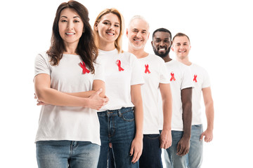 Wall Mural - happy group of people in blank white t-shirts standing in row with aids awareness red ribbons isolated on white