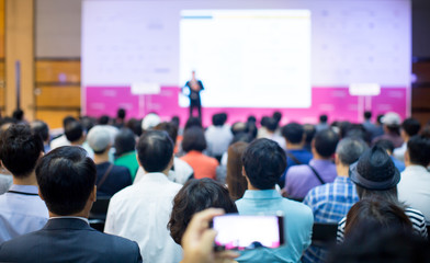 Fototapete - Audience at Conference Listen to Tech Executive Speaker Giving Presentation at Seminar. Convention Event Lecture. Business Presenter with Hand on Hip. Business Coach Speaker. Corporate Technology Man.