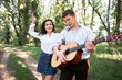 © soleg - young couple walking in the forest, playing guitar and dancing, summer nature, bright sunlight, shadows and green leaves, romantic feelings