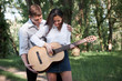 © soleg - young couple walking in the forest, playing guitar and dancing, summer nature, bright sunlight, shadows and green leaves, romantic feelings