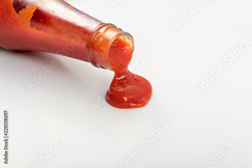 Fotografie, Obraz Tomato sauce is poured from the glass bottle on white background