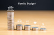 STACKED US QUARTER COINS ON WOODEN TABLE SHOWING FAMILY BUDGET (MORTGAGE, TRANSPORTATION, FOOD, HEALTHCARE, SAVING) / FINANCIAL CONCEPT